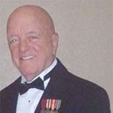 A Man and Woman in Formal Attire Stand Beside a Large Cardboard Cutout of a Uniformed Man, Smiling at the Camera.